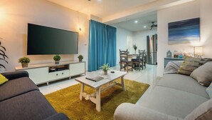 Una sala de estar moderna con un televisor de pantalla plana, un sofá, una mesa de centro y un comedor con sillas y una mesa.