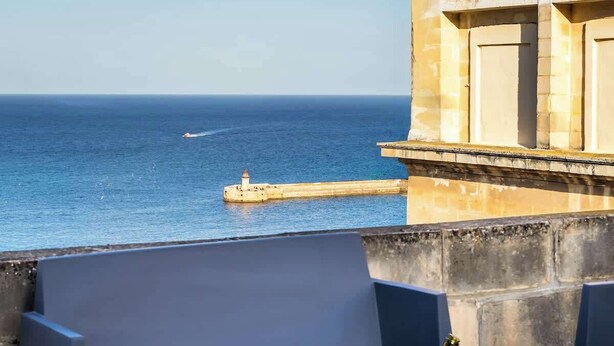 Una terraza con una mesa dispuesta para dos, con vista a un cuerpo de agua y un muelle.