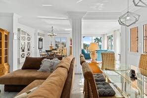 A spacious living area with a sofa, chairs, a dining table, and a view of the outdoors. - Villa 'Sunrise Benalmádena' with Sea Views, Wi-Fi, and Air Conditioning (Benalmádena)
