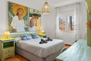 A bedroom with a bed, two bedside tables, a hanging light fixture, a window with bars, and artwork on the wall. - Villa 'Sunrise Benalmádena' with Sea Views, Wi-Fi, and Air Conditioning (Benalmádena)