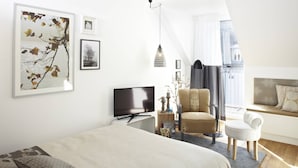 A modern bedroom with a bed, a TV, a chair, a sofa, and artwork on the walls. - KÖNIGSschlafs cuddly nest for 2 persons with sunny balcony (Konstanz)