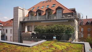 A two-story building with a red-tiled roof, balconies, and a garden area with green plants. - KÖNIGSschlafs cuddly nest for 2 persons with sunny balcony (Konstanz)