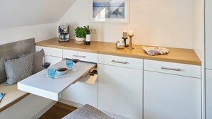 A modern kitchen with a wooden countertop, a built-in coffee machine, a small plant, a candle, and a newspaper. - KÖNIGSschlafs cuddly nest for 2 persons with sunny balcony (Konstanz)