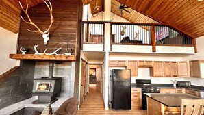 Une cuisine spacieuse de style loft, dotée d’un îlot central, de meubles en bois et d’une cheminée en pierre.
