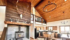 Un vaste espace de vie agrémenté d’une cheminée en pierre, d’un plafond en bois et d’un coin salon confortable.