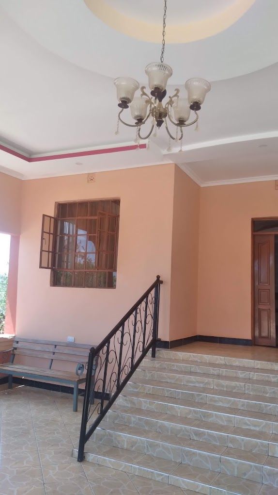 A staircase with a black railing leading to a landing, a bench, and a window with a view of greenery.
