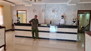 A reception desk with a 'RECEPTION' sign, two clocks, and a vase with flowers. - Hoyjiifka Holale Resort (Moyale)