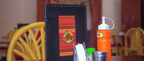 A table with a black leather wallet, an orange bottle, a silver container, and a green bottle.