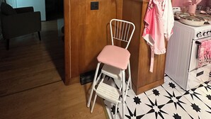 Una cocina con una estufa blanca, un reloj rosa y un aviso enmarcado en la pared.