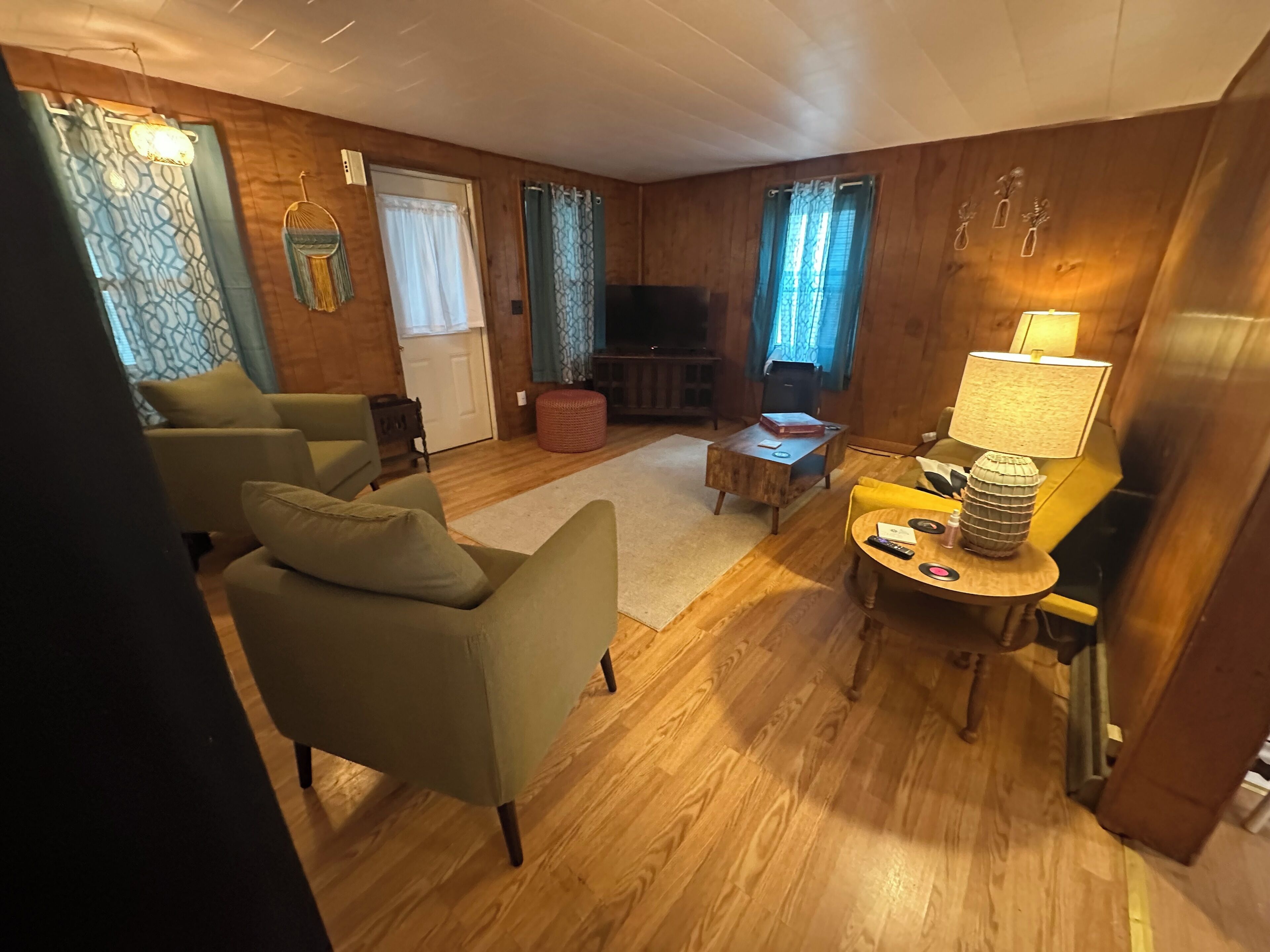 Een gezellige woonkamer met houten vloeren, een bank, een salontafel en een televisie.