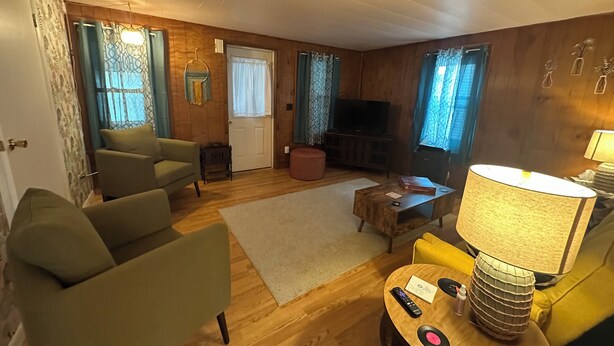 Una sala de estar acogedora con paredes de madera, un sofá, una mesa de centro y un televisor.