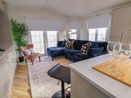 A modern living room with a blue sofa, a coffee table, and a bar area with two glasses.