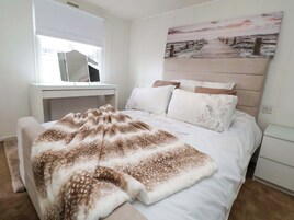 Un dormitorio con una cama, una mesita de noche, un escritorio y un cuadro en la pared.
