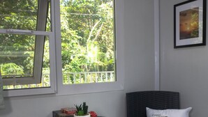 Ett litet rum med ett fönster, ett bord med en växt och två stolar.