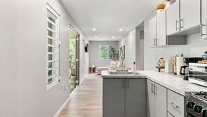 Une cuisine moderne avec des meubles gris, un îlot central et un four encastré.
