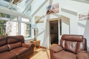 A room with two leather sofas, a small table with a lamp, and a glass ceiling. - Blowing House Cottage (Perranporth)