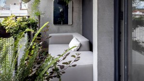 A modern balcony with a white sofa, hanging plants, and a concrete wall. - Casa Gama Gabriel | Art and Design in Northern Rome (Ciudad de México)