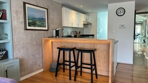 Eine moderne Küche mit einer Holztischinsel, Barhocker und einer Wanduhr.