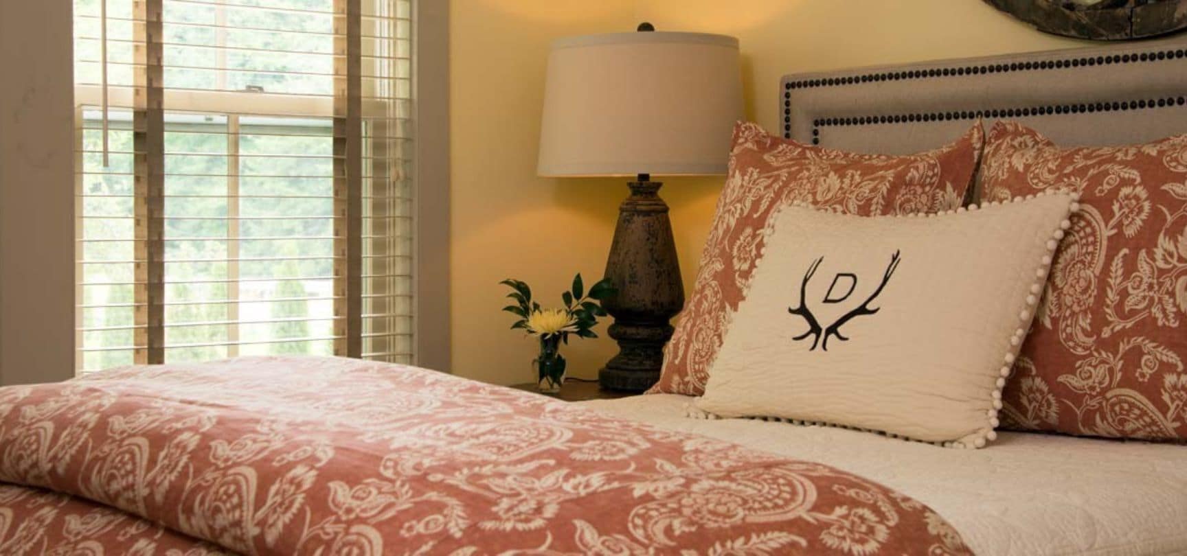 Une chambre à coucher avec un lit, une table de chevet avec une lampe et une fenêtre avec des stores.