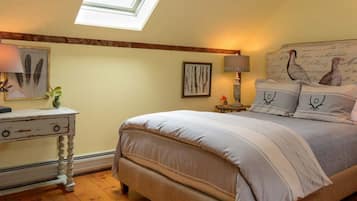 A bedroom with a bed, two bedside tables, a nightstand, a skylight, and wall art.