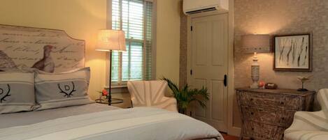 A bedroom with a bed, a chair, a dresser, and a lamp.