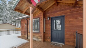 Une cabane en bois avec une porte bleu foncé, un petit porche et un sol recouvert de neige.