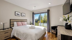 A bedroom with a large bed, bedside tables, a desk, and a TV. - Ski & relax with a view of the river - L'Aube Charlevoix (Petite-Rivière-Saint-François)
