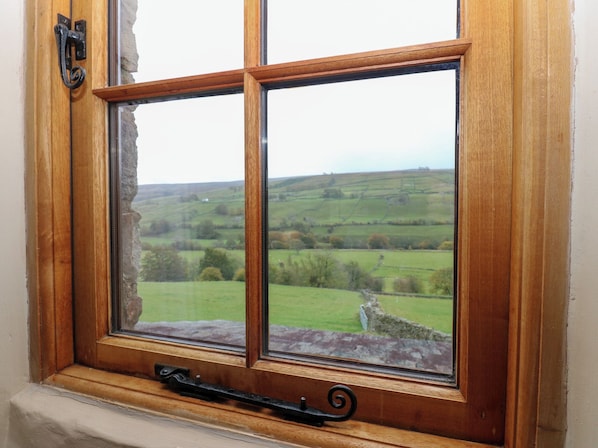 A window with a view of a green landscape and stone wall. - Nick Jone (Richmond)