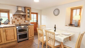A kitchen with wooden cabinets, a stove, and a dining table set for two. - Nick Jone (Richmond)