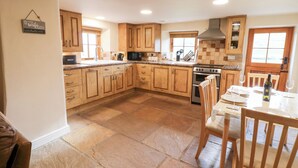 A spacious kitchen with wooden cabinets, a granite countertop, and a dining area with a table set for two. - Nick Jone (Richmond)