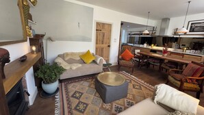 A cozy living room with a sofa, ottoman, and a dining area with a table and chairs. - Bohemian Beach Cottage (Bournemouth)