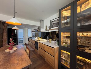 Een moderne keuken met een centraal eiland, houten keukenkastjes en een eethoek met een houten tafel en stoelen.
