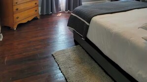 Un dormitorio con un aparador de madera, una cama grande y cortinas grises.