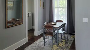 Un comedor con una mesa y sillas, un espejo grande y una lámpara en el techo.