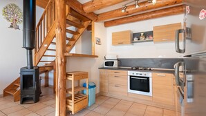 A kitchen with wooden cabinets, a stove, a microwave, and a refrigerator. - Mountain House for 9 Guests (Saint-Lary Soulan)