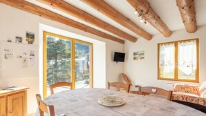 A dining area with a round table, wooden chairs, a cabinet, and a television on the wall. - Mountain House for 9 Guests (Saint-Lary Soulan)