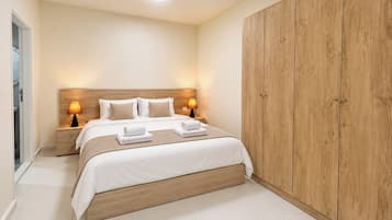 A hotel room with a large bed, wooden wardrobe, bedside lamps, and a ceiling light.