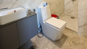A modern bathroom with a marble backsplash, a large mirror, a white sink, and a shower with a handheld showerhead. - C Beirut Hotel & Appartment (Mar Roukouz)