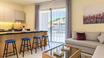 A modern living room with a sofa, a coffee table, and a kitchen area with a bar stool.