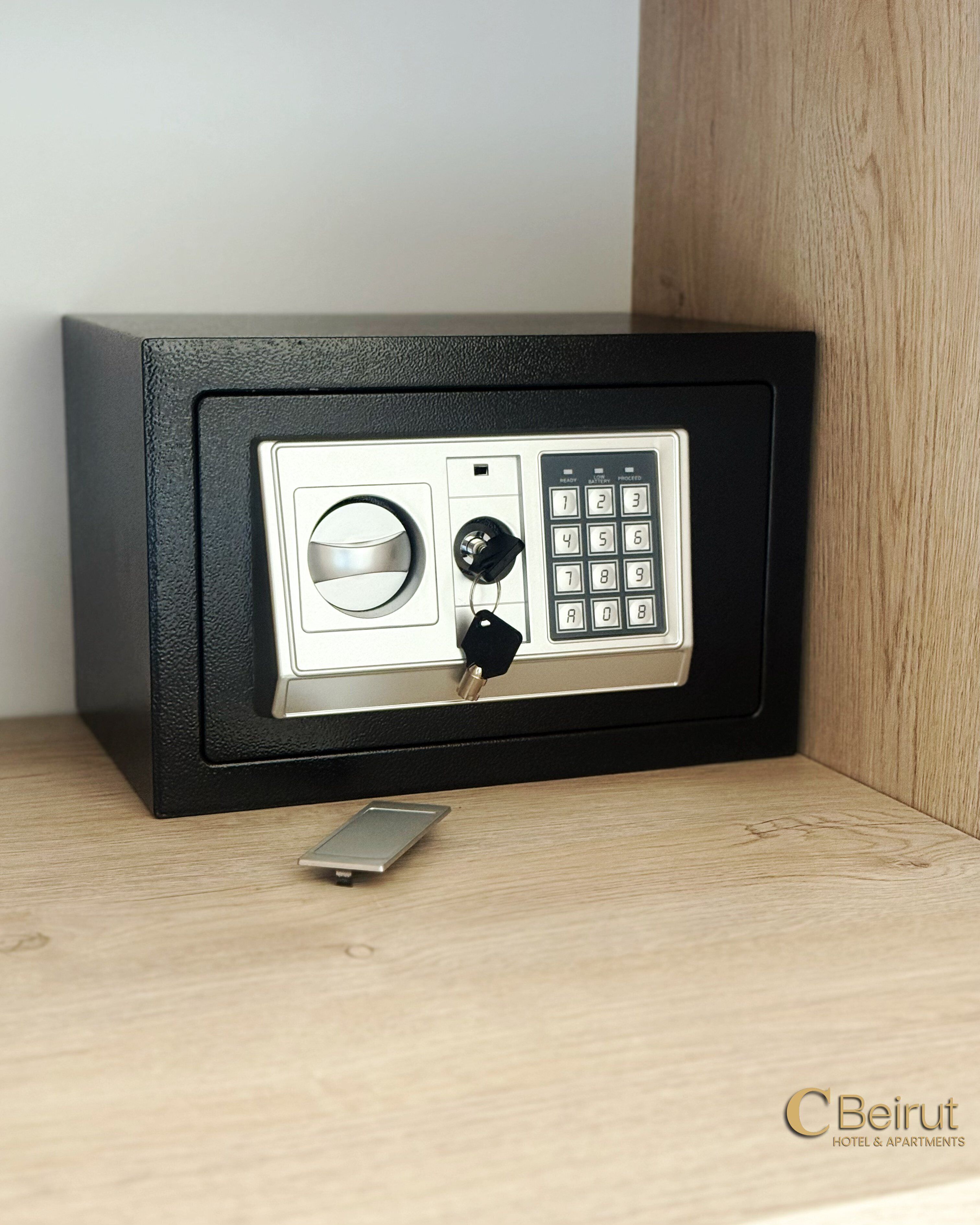 A safe with a combination dial and keypad, a keyhole, and a key inserted.