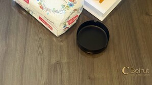 Un paquete de papel higiénico Avera Green, un libro titulado 'Louis Vuitton' y un pequeño adorno sobre una mesa de madera.