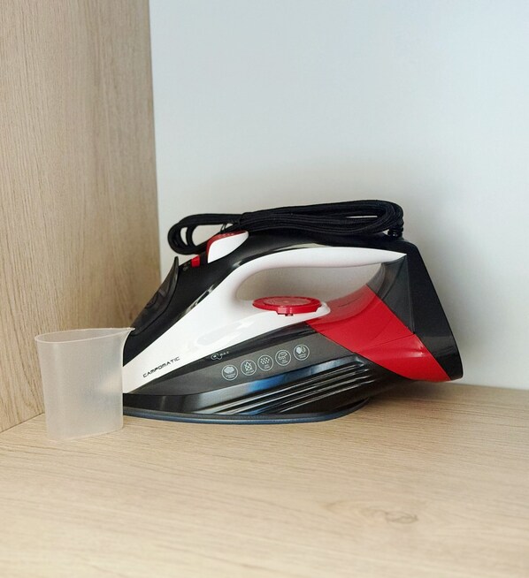 A black and red iron with a transparent water container on a wooden surface.