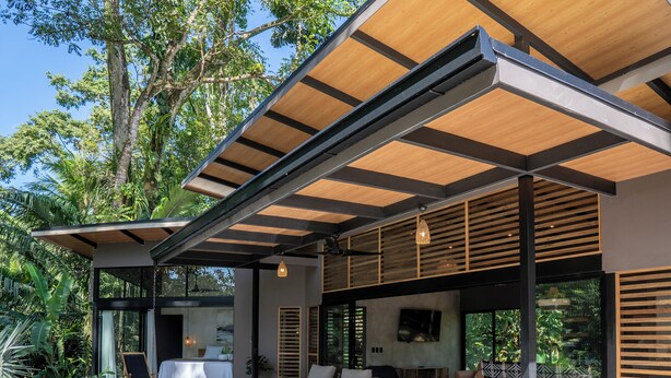 Una casa moderna con piscina, terraza de madera y zona de estar al aire libre.