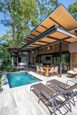 A modern house with a pool, wooden deck, and outdoor seating area. - Villa Asencia (Punta Uva)