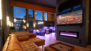 Een moderne woonkamer met een grote bank, een houten salontafel en een aan de muur bevestigde televisie.