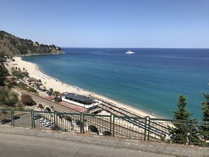 A coastal beach with a clear view of the sea, a boat in the distance, and a parking area with cars. - Calabria - Soverato - Caminia - Pietragrande - Copanello (STALETTÌ (CZ))