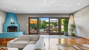 A modern living room with a sectional sofa, a fireplace, and a view of an outdoor patio with a pool. - Bel Air Mid-Mod Oasis w/ Grotto Pool + Jacuzzi (Los Angeles)