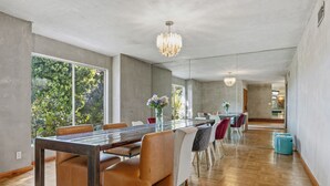 A spacious dining area with a long wooden table, leather chairs, and a chandelier. - Bel Air Mid-Mod Oasis w/ Grotto Pool + Jacuzzi (Los Angeles)