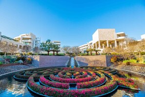 A modern building with a circular water feature in the foreground. - Bel Air Mid-Mod Oasis w/ Grotto Pool + Jacuzzi (Los Angeles)