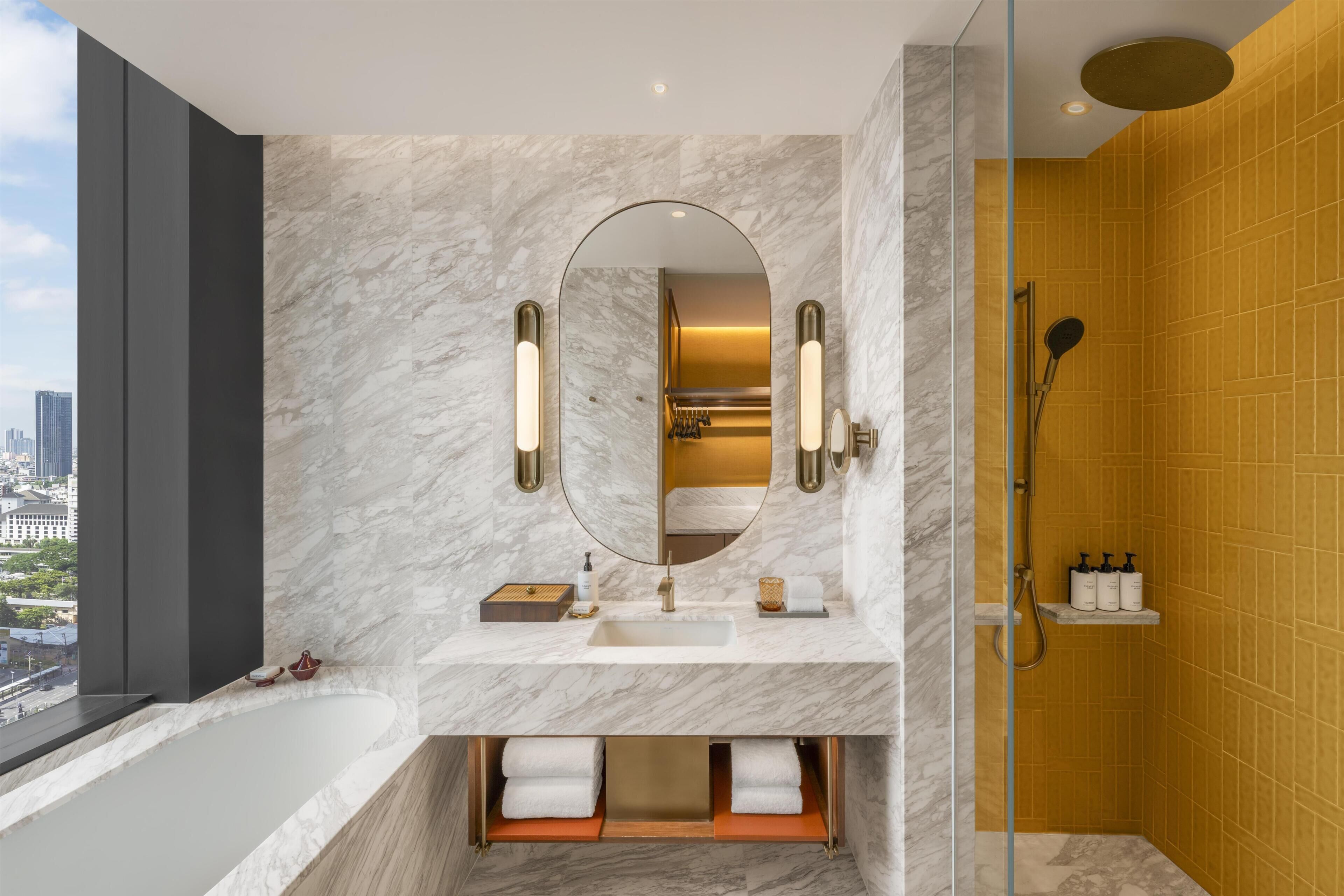 A modern bathroom with a marble vanity, a large mirror, a bathtub, and a shower area.